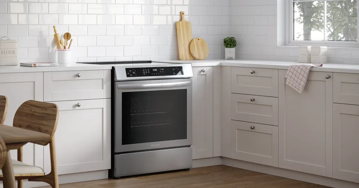 Stainless steel Frigidaire 30-inch front control induction range (FCFI3083AS) installed in a modern white kitchen.